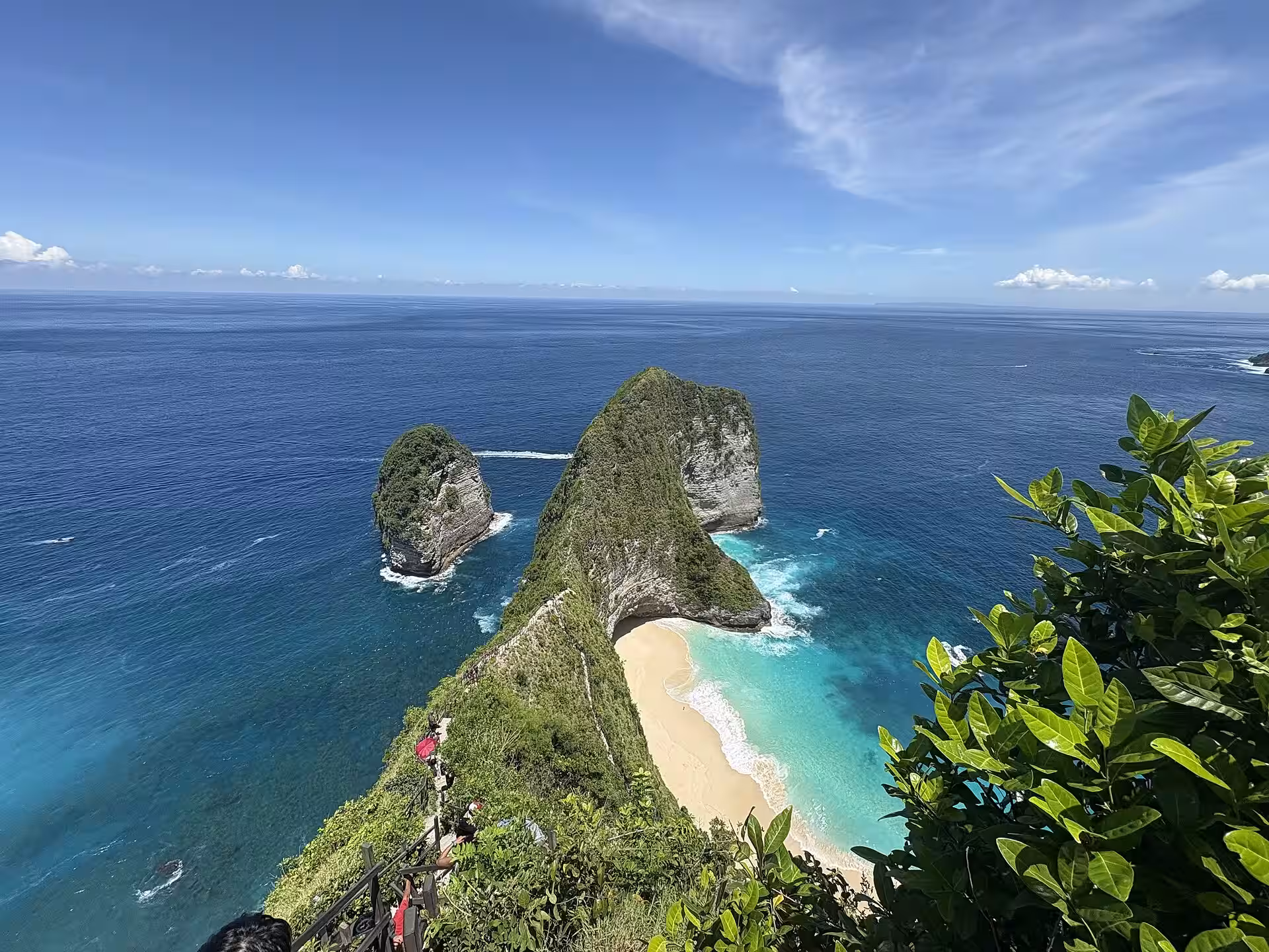 Wide overview of Kelingking headland, white-sand cove and offshore rock from the viewpoint